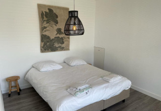 Camera moderna al Mode Sauna, De Zanding, Paesi Bassi, con letto matrimoniale, pareti bianche e decor minimalista.