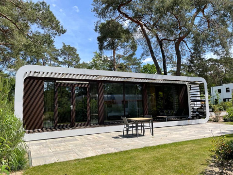 Moderne lodge Mode Sauna in De Zanding, Nederland, omgeven door bomen en voorzien van een terras.