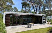 Moderne Lodge Mode Sauna bei De Zanding in den Niederlanden mit Terrasse und von Bäumen umgeben.