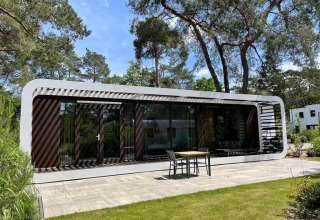 Moderne lodge Mode Sauna in De Zanding, Nederland, omgeven door bomen en voorzien van een terras.