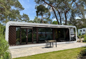 Moderne lodge Mode Sauna in De Zanding, Nederland, omgeven door bomen en voorzien van een terras.