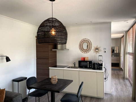Moderne lodgekeuken met eetruimte en gevlochten hanglamp bij Mode Sauna, De Zanding, Nederland.