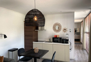 Moderne lodgekeuken met eetruimte en gevlochten hanglamp bij Mode Sauna, De Zanding, Nederland.