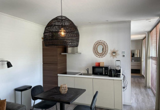 Moderne lodgekeuken met eetruimte en gevlochten hanglamp bij Mode Sauna, De Zanding, Nederland.