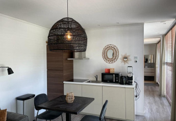 Moderne lodgekeuken met eetruimte en gevlochten hanglamp bij Mode Sauna, De Zanding, Nederland.