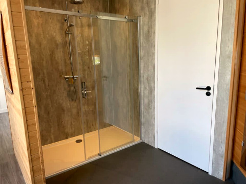 Moderne douche met glazen deuren naast een witte deur bij Mode Sauna, De Zanding, Nederland.
