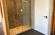 Moderne Duschkabine mit Glasfront neben einer weißen Tür im Mode Sauna, De Zanding, Niederlande.