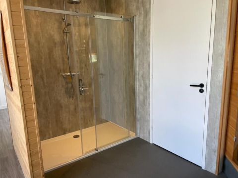 Moderne Duschkabine mit Glasfront neben einer weißen Tür im Mode Sauna, De Zanding, Niederlande.