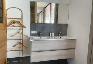 Bagno moderno presso Mode Sauna, De Zanding nei Paesi Bassi, con doppi lavandini, specchio e portabiti.