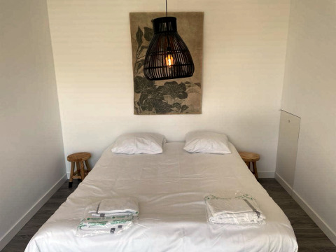 Slaapkamer in Mode Sauna bij De Zanding, Nederland, met tweepersoonsbed, lampen en wanddecoratie.