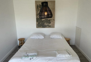 Schlafzimmer im Mode Sauna bei De Zanding, Niederlande, mit Doppelbett, Lampen und Wandkunst.