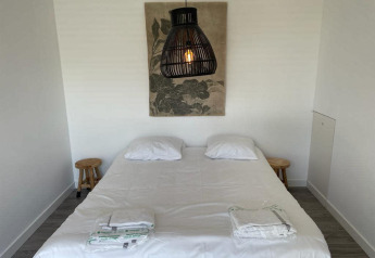 Slaapkamer in Mode Sauna bij De Zanding, Nederland, met tweepersoonsbed, lampen en wanddecoratie.