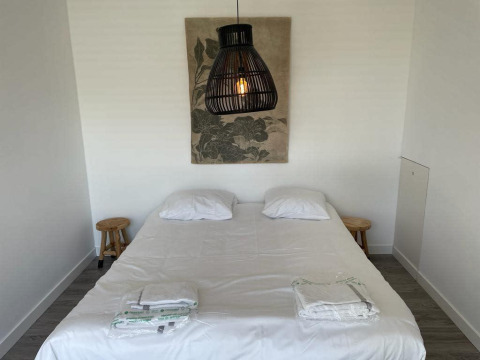 Dormitorio en Mode Sauna de De Zanding, Países Bajos, con cama doble, lámparas y arte en la pared.