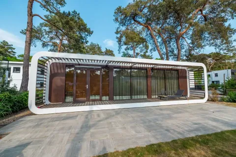 Modernes Mode Sauna-Lodge bei De Zanding in den Niederlanden, umgeben von hohen Bäumen und stilvollem Ambiente.