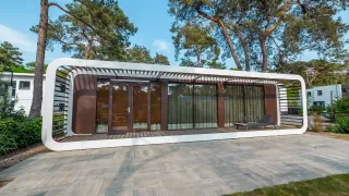 Modernes Mode Sauna-Lodge bei De Zanding in den Niederlanden, umgeben von hohen Bäumen und stilvollem Ambiente.