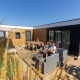 Familie nyder solen foran Zonneweelde Lodge XL ved Camping Zonneweelde i Holland, omgivet af natur og komfort.