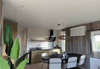 Sala y cocina modernas en Zonneweelde Lodge XL, Camping Zonneweelde, Países Bajos, con mesa de comedor.