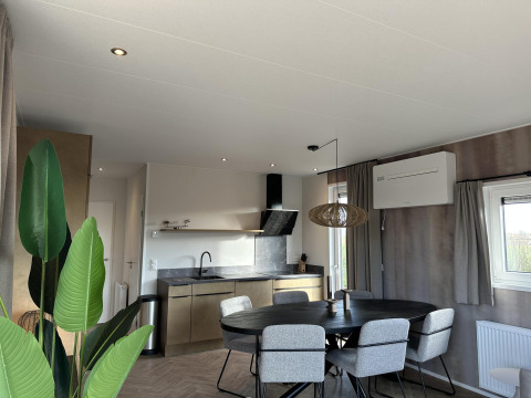 Sala y cocina modernas en Zonneweelde Lodge XL, Camping Zonneweelde, Países Bajos, con mesa de comedor.