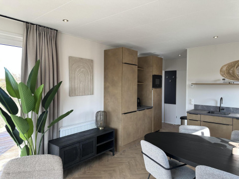 Salón y cocina modernos en Zonneweelde Lodge XL en Camping Zonneweelde, Países Bajos, con decoración elegante.