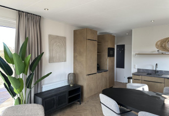 Moderne leefruimte en keuken in Zonneweelde Lodge XL op Camping Zonneweelde, Nederland, met stijlvol interieur.