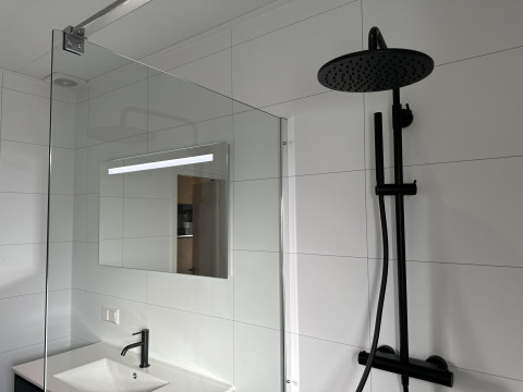 Salle de bain moderne avec douche noire, lavabo et miroir à Zonneweelde Lodge XL, Camping Zonneweelde, Pays-Bas.