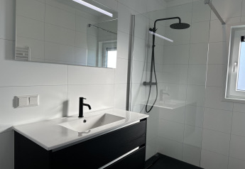 Bagno moderno con rubinetto nero, grande specchio e doccia walk-in nella Zonneweelde Lodge XL, Paesi Bassi.