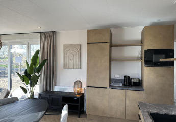 Soggiorno e cucina moderni nella Zonneweelde Lodge XL al Camping Zonneweelde, Paesi Bassi, arredo elegante.