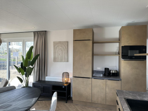 Moderne stue og køkken i Zonneweelde Lodge XL på Camping Zonneweelde i Holland med elegante møbler.