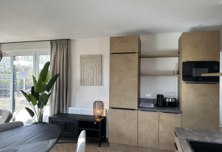 Sala y cocina modernas en Zonneweelde Lodge XL en Camping Zonneweelde, Países Bajos, con decoración elegante.