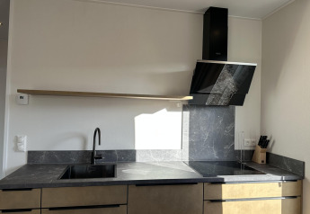Moderne keuken in Zonneweelde Lodge XL, Camping Zonneweelde, Nederland, met marmeren blad en zwarte kraan.