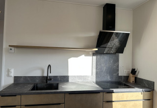 Cocina moderna en Zonneweelde Lodge XL, Camping Zonneweelde, Países Bajos, con encimera de mármol y campana.