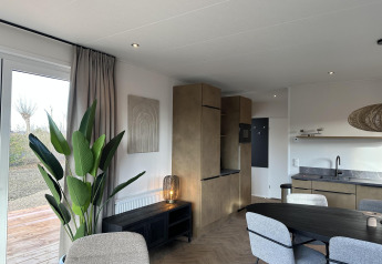 Modern interieur van Zonneweelde Lodge XL bij Camping Zonneweelde in Nederland, met eethoek en planten.