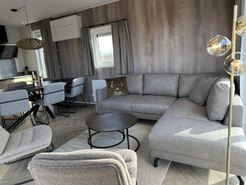 Salon moderne dans la Zonneweelde Lodge XL au Camping Zonneweelde, Pays-Bas, avec mobilier gris élégant.