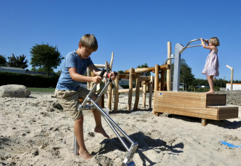 Kinderen spelen in het zand bij Zonneweelde Lodge XL op Camping Zonneweelde in Nederland op een zonnige dag.