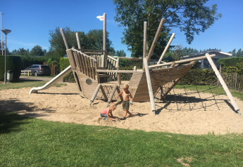 Bambini che giocano su un grande parco giochi a forma di nave a Camping Zonneweelde, Zonneweelde Lodge XL nei Paesi Bassi.