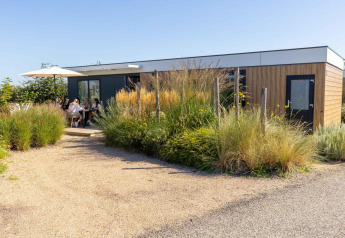 Lodge Zonneweelde au Camping Zonneweelde aux Pays-Bas, personnes assises sous un parasol blanc.