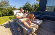 Pareja relajándose en tumbonas en Zonneweelde Lodge, Camping Zonneweelde, Países Bajos, disfrutando el sol.