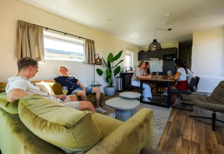 Venner nyder tid sammen i Zonneweelde Lodge på Camping Zonneweelde i Holland, afslappet og smilende.