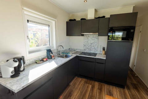 Moderne keuken met donkere kasten en marmerlook aanrecht in Zonneweelde Lodge op Camping Zonneweelde.