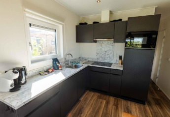 Modern kitchen with dark cabinets and marble-style countertops in Zonneweelde Lodge at Camping Zonneweelde.