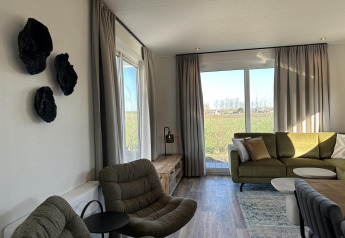 Soggiorno moderno presso Zonneweelde Lodge al Camping Zonneweelde, Paesi Bassi, con ampie finestre e arredi chic.