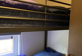 Literas con ropa de cama azul y morada en Zonneweelde Lodge, Camping Zonneweelde, Países Bajos.