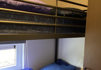 Literas con ropa de cama azul y morada en Zonneweelde Lodge, Camping Zonneweelde, Países Bajos.