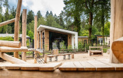 Parque infantil con estructuras de madera frente a cabañas modernas en Resort Veluwe, Silva, Países Bajos, bosque.