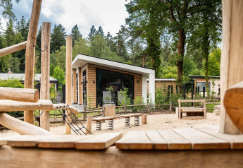 Parco giochi con strutture in legno davanti a lodge moderni al Resort Veluwe, Silva, nei Paesi Bassi in natura.