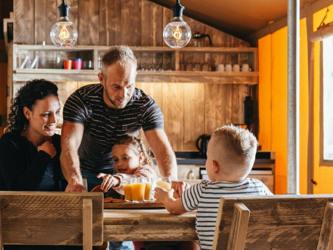 En familie nyder morgenmad sammen i safari teltet Vecht Glamping Lodge på Beerze Bulten i Holland.