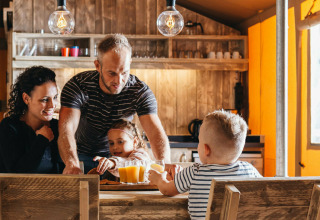 En familie nyder morgenmad sammen i safari teltet Vecht Glamping Lodge på Beerze Bulten i Holland.