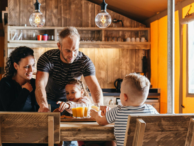 Eine Familie frühstückt gemeinsam im Safari-Zelt Vecht Glamping Lodge bei Beerze Bulten in den Niederlanden.
