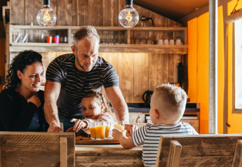 A family enjoys breakfast together inside the safari tent Vecht Glamping Lodge at Beerze Bulten, Netherlands.