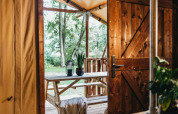 Uitzicht vanuit een safaritent in Vecht Glamping Lodge, Beerze Bulten, met houten tafel en groen zicht.